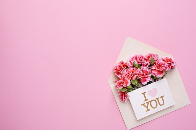 An envelope with pink flowers and a card I love you on pink