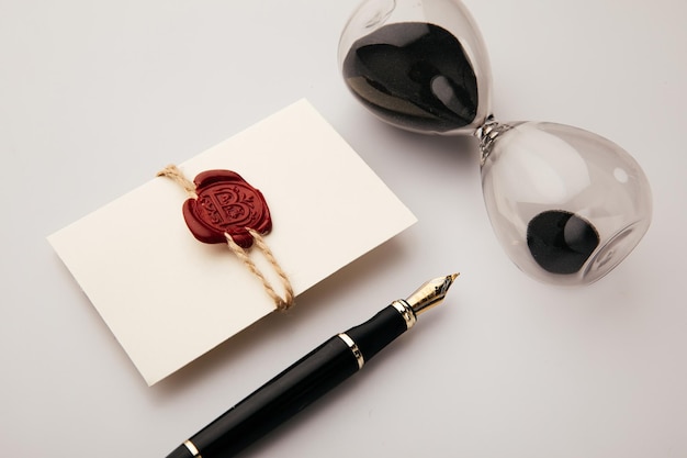 Envelope with red wax seal pen and hourglass closeup