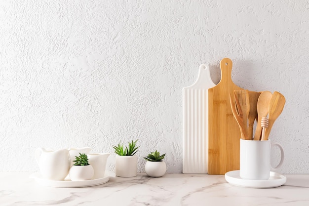 Environmentally friendly items of modern tableware on a white marble countertop with green plants in minihills space for text minimalist style