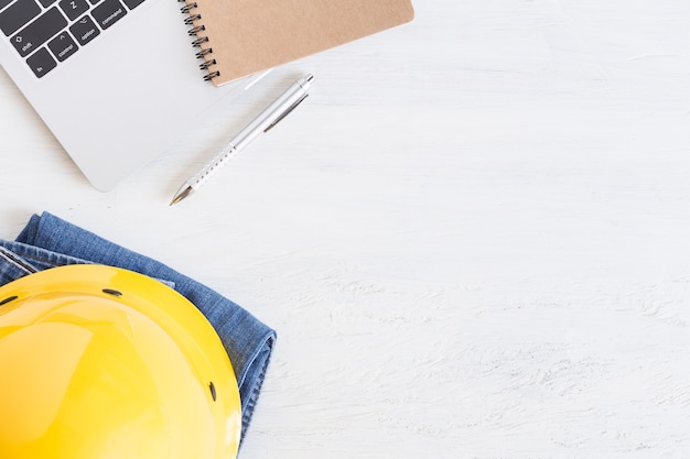 Equipment works on white wooden floor, yellow helmet and notebook