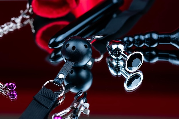 Erotic bdsm toys for intimate sex games gag in the mouth with leather straps on the background of a vibrator and silicone anal plug