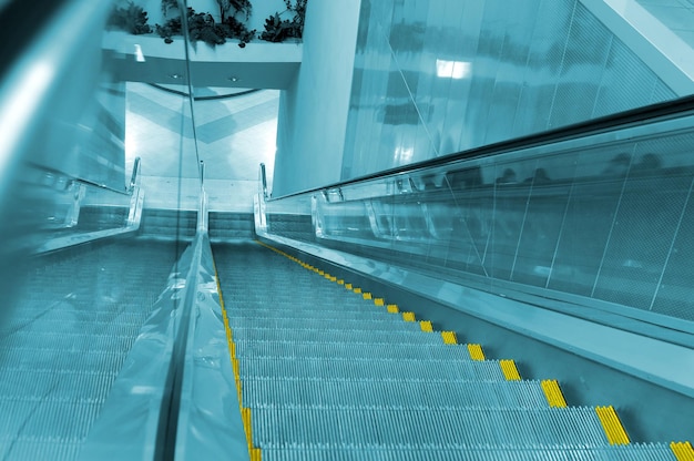 An escalator with a blue background and a yellow sign that says escalator.