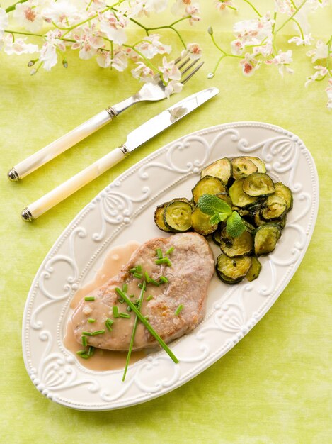 Escalope with white wine sauce and sauteed zucchinis