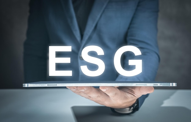 ESG environmental social governance business strategy investing concept businessman hand with tablet and ESG text