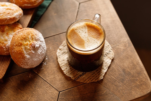 Espresso coffee in a glass mug with cheesecake on a wooden background