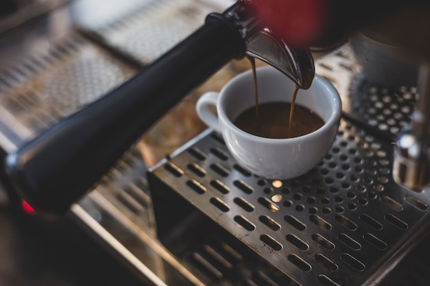 Espresso extraction from coffee machine in coffee shop.