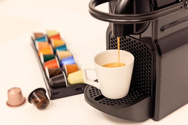 Espresso machine in black color prepares espresso coffee capsules around Close up view details