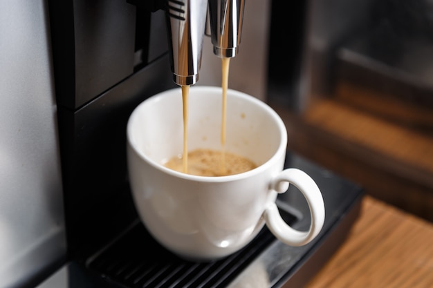 Espresso machine pouring coffee in white cup