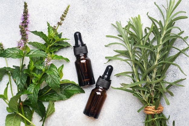 Essential aroma oil in dark glass bottles with peppermint and rosemary