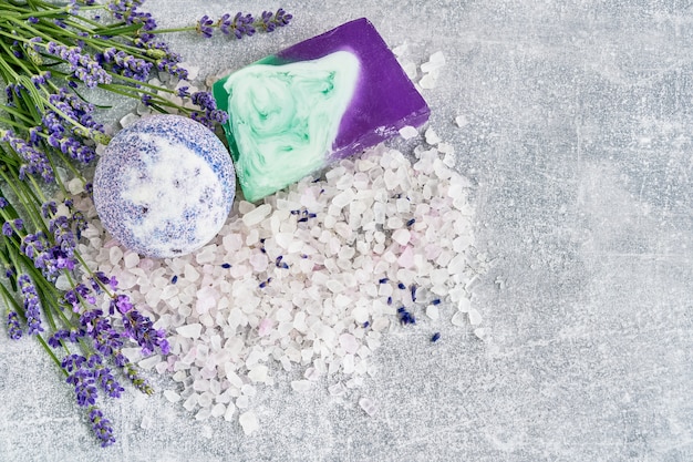 Essential lavender salt, soap and bath bomb with flowers top view. SPA lavender products.