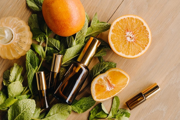 Essential oil in bottles with the aroma of orange and mint lying on a wooden surface