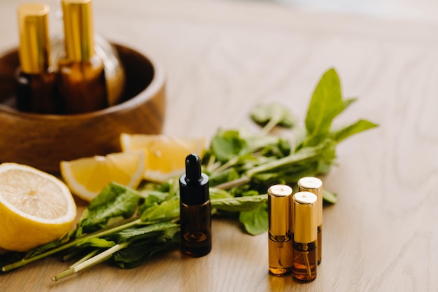 Essential oil in bottles with lemon and mint fragrance lying on a wooden surface