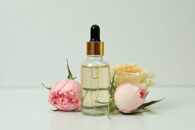 Essential rose oil and roses on white