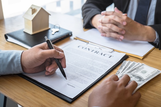 Estate agent are presenting home loan and giving house, keys to customer after signing contract