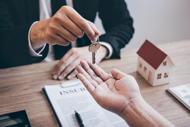 Estate agent giving house keys to client after signing agreement contract real estate with approved mortgage application form, concerning mortgage loan offer for and house insurance.