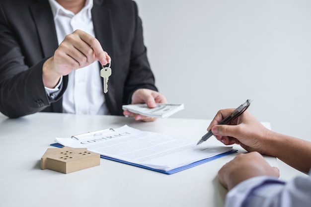 Estate agent giving house keys to client after signing agreement contract real estate with approved