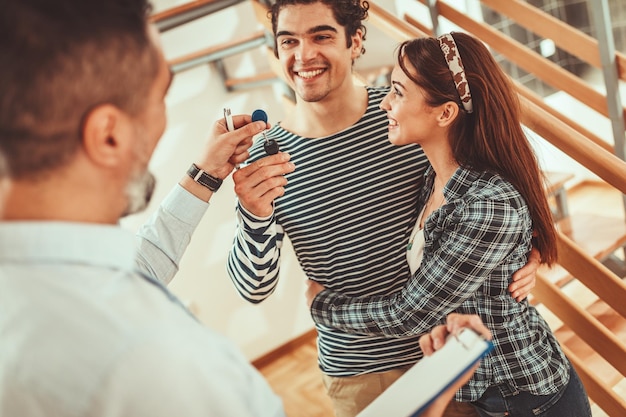 Estate agent is showing house to couple buyers and giving them key of their new home.