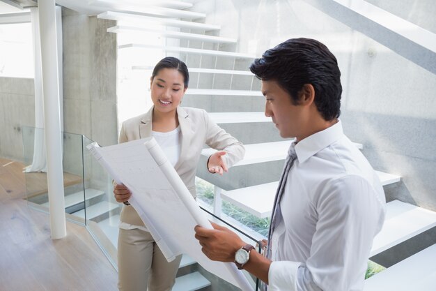 Estate agent looking at blueprint with potential buyer