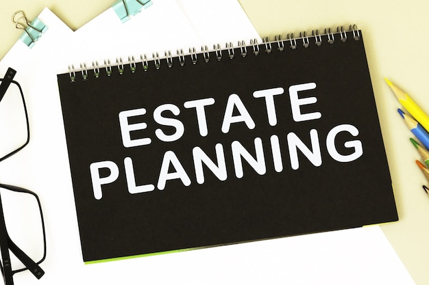 ESTATE PLANNING. Office supplies, alarm clock, block with text. Business, education concept. flat lay