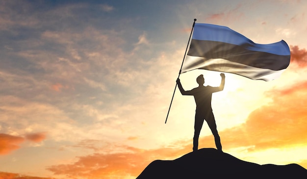 Estonia flag being waved by a man celebrating success at the top of a mountain 3D Rendering