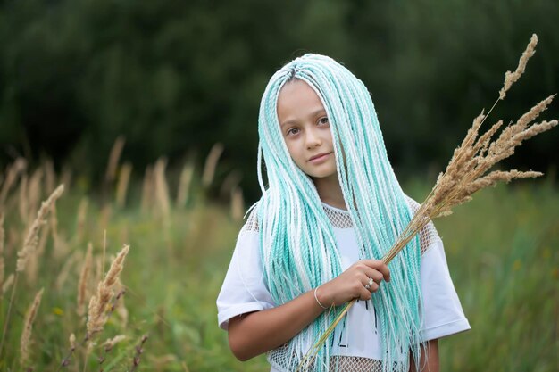 Ethnic little girl with African braids holds a bunch of grass panicles and looks at the camera