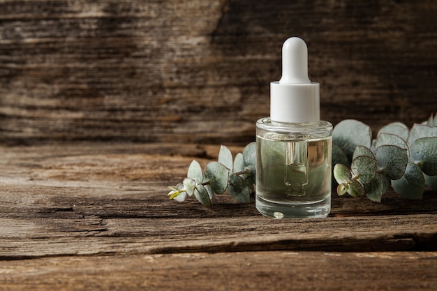 Eucalyptus essential oil and fresh eucalyptus leaves on wood