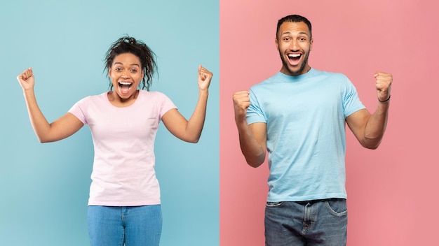 Euphoric black couple shaking clenched fists exclaiming with excitement standing over halved pink and blue background