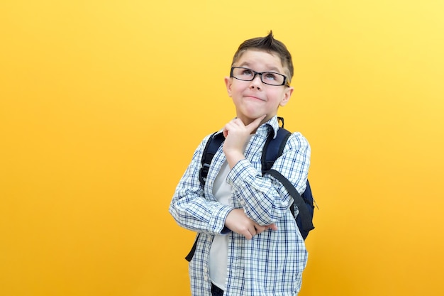 Eureka handsome little boy in glasses is surprised inspired i have an idea raise your index finger up copy space isolated on yellow background schoolboy