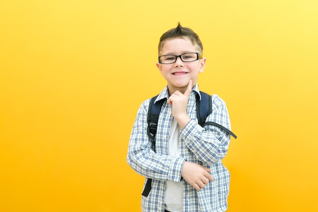 Eureka handsome little boy in glasses is surprised inspired i have an idea raise your index finger up copy space isolated on yellow background schoolboy