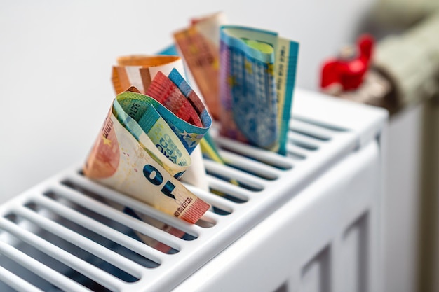 Euro banknotes in a central heating radiator the concept of expensive heating costs closeup