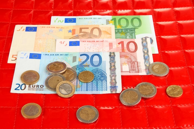 Euro banknotes and euro cents on red background