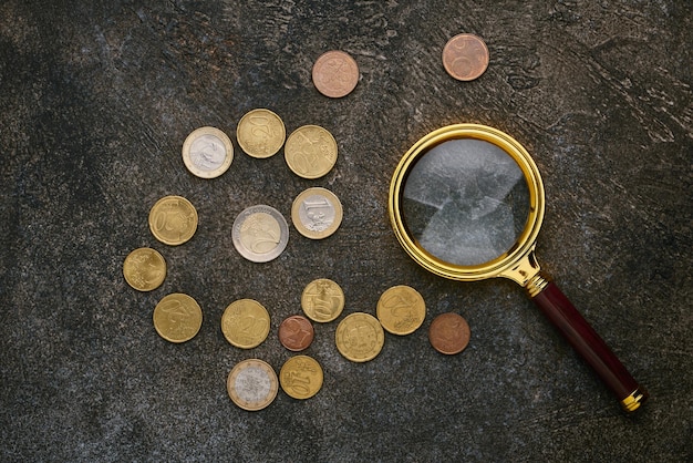 Euro cents and a magnifying glass on dark background