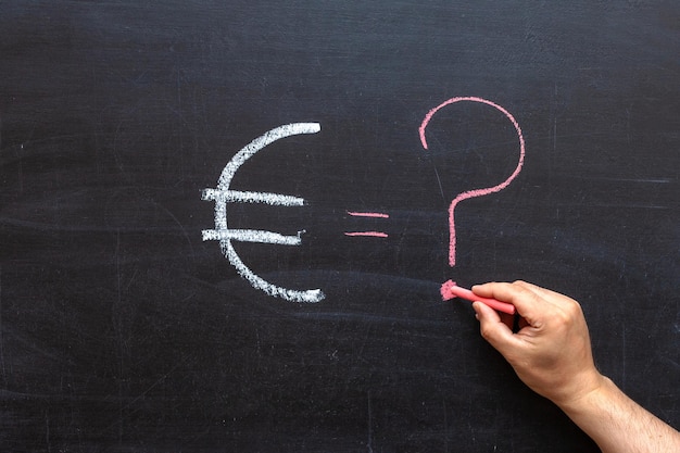 The Euro symbol and a question mark on the chalk Board. blackboard