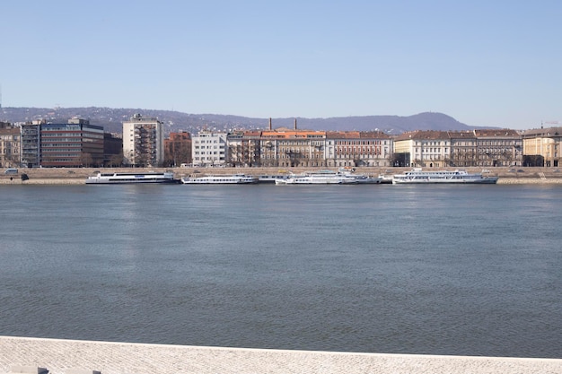 Europe Budapest Danube river Kravid ashore with ferries and buildings City on the water