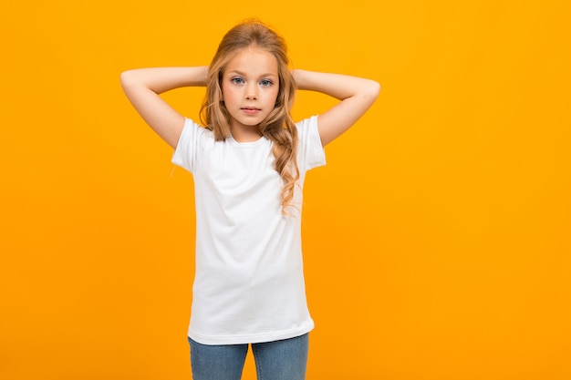 European attractive girl in a white T-shirt with a mockup on a yellow