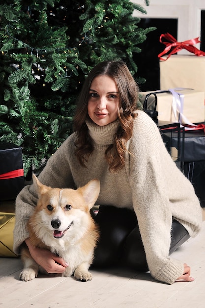 European caucasian young woman is sitting under a Christmas tree