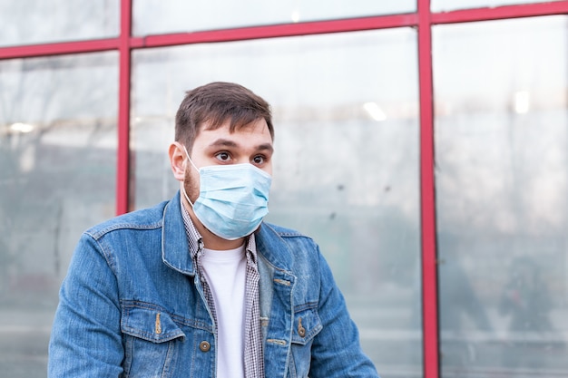 European coronavirus. Portrait of caucasian man wearing facial hygienic mask, respiratory protection mask outdoors. Virus, coronavirus protection, air pollution, ecology, environmental awareness.