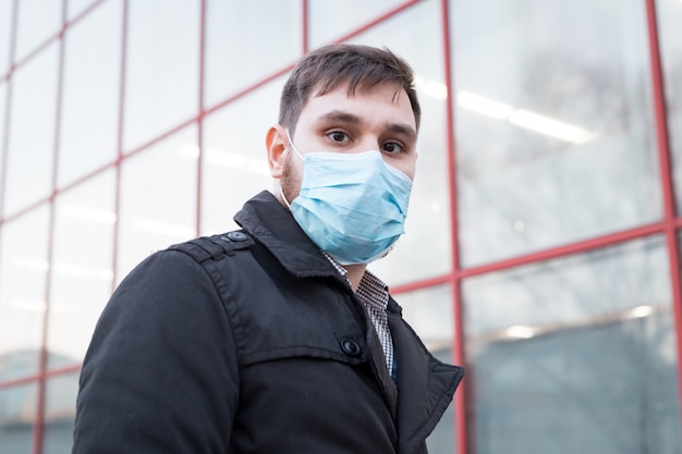 European coronavirus. Portrait of caucasian man wearing facial hygienic mask, respiratory protection mask outdoors. Virus, coronavirus protection, air pollution, ecology, environmental awareness.