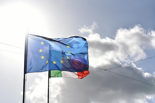 European flag and italian flag waving together in a clear blue sky Relationship between the European Union and the Italy Concepts