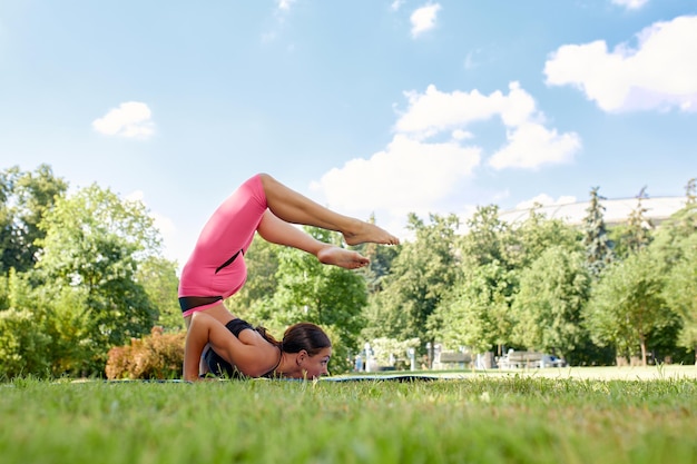 European girl in a light tracksuit doing yoga in the park in the afternoon in the summer Gymnastics in nature Thin woman outdoor