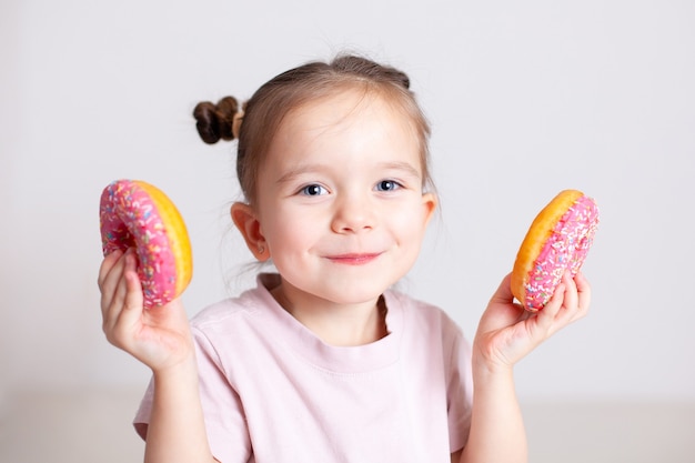 A European girl with blue eyes holds doughnuts and laughs Portrait on a white background