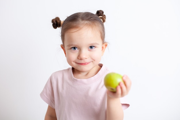 European girl with blue eyes holds a green apple in her hand