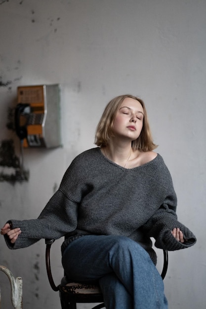 A European girl with short blonde hair poses in a knitted sweater for a clothing catalog