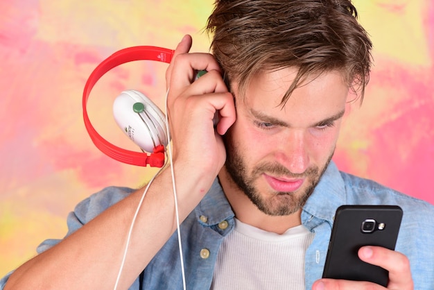 European guy have fun time. Musical lifestyle. Cheerful teenage dj listening songs via earphones. Blue eyed stylish hipster with smartphone. American handsome bearded guy with headphones.