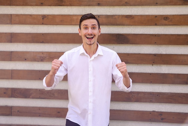 European guy in a white shirt winning a prize on a brown ribbed background with copy space