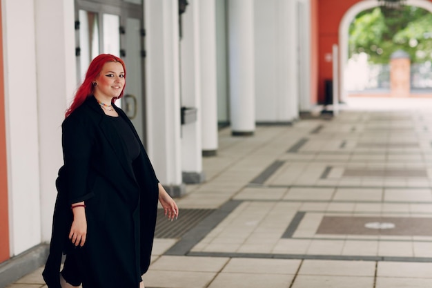 European plus size woman walking outdoor street city Young red pink haired body positive girl