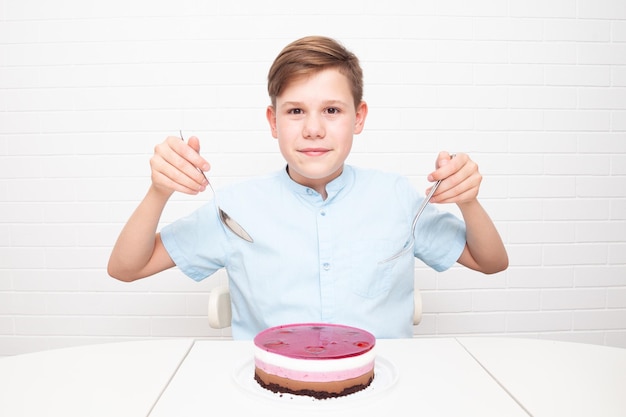 European Teenager on a white background with cutlery wants to eat a cake