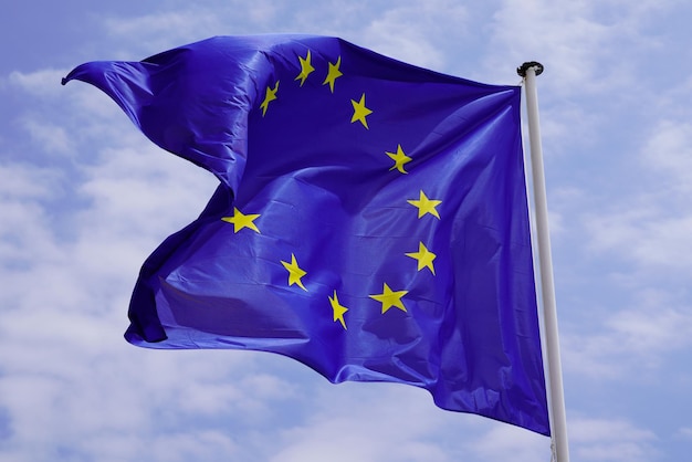 European Union EU Flag yellow stars Waving in mat on cloud blue sky background