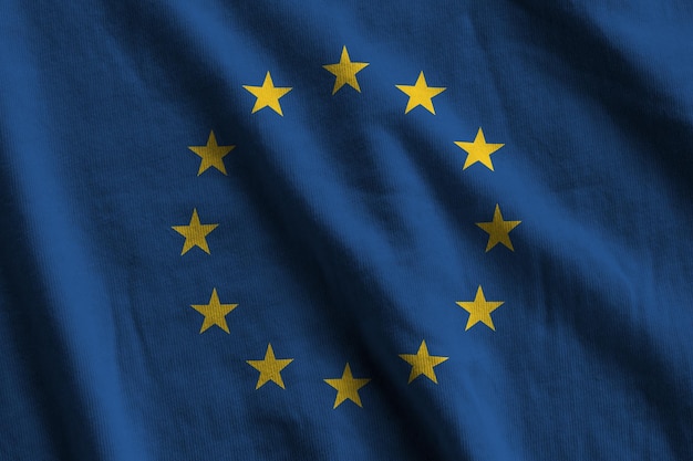 European union flag with big folds waving close up under the studio light indoors The official symbols and colors in banner