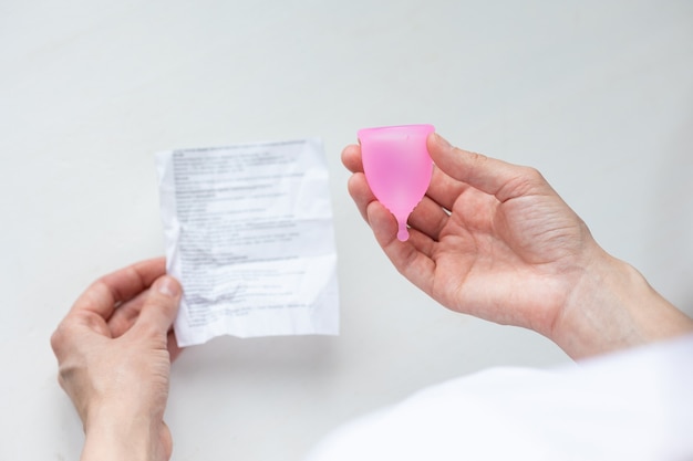 A european woman holds a pink menstrual cup made of silicone in her hands